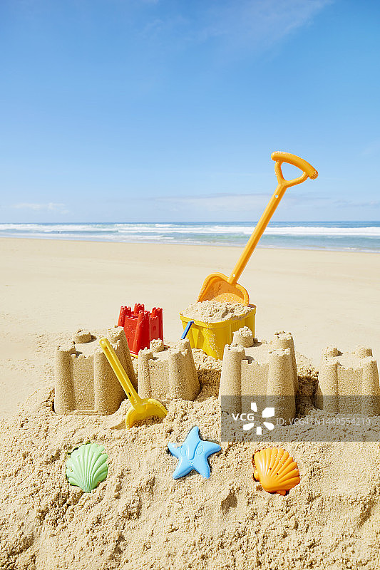 沙滩和大海边的大型沙堡与彩色玩具图片素材
