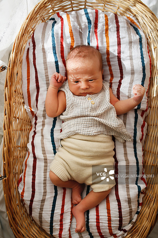 新生儿躺在棉质尿布上的柳条筐里，睁着眼睛环顾四周图片素材