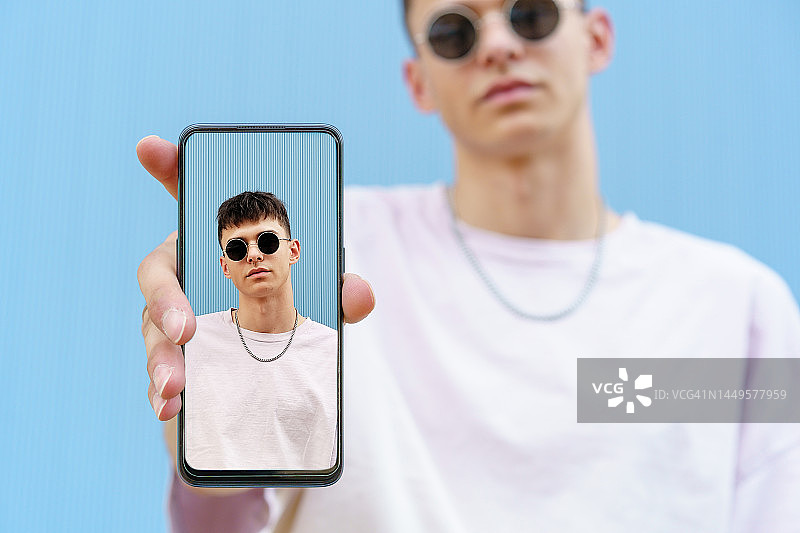 年轻白人男子手持显示城市照片的智能手机屏幕图片素材