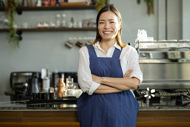 咖啡店的服务和质量对于提高销量非常重要。一位日本咖啡店女老板站在咖啡店的收银台前图片素材
