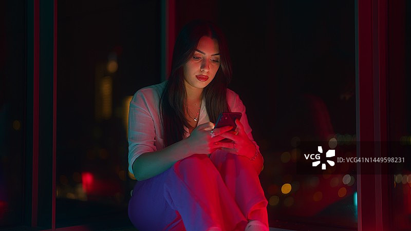 年轻女人晚上在家使用智能手机图片素材