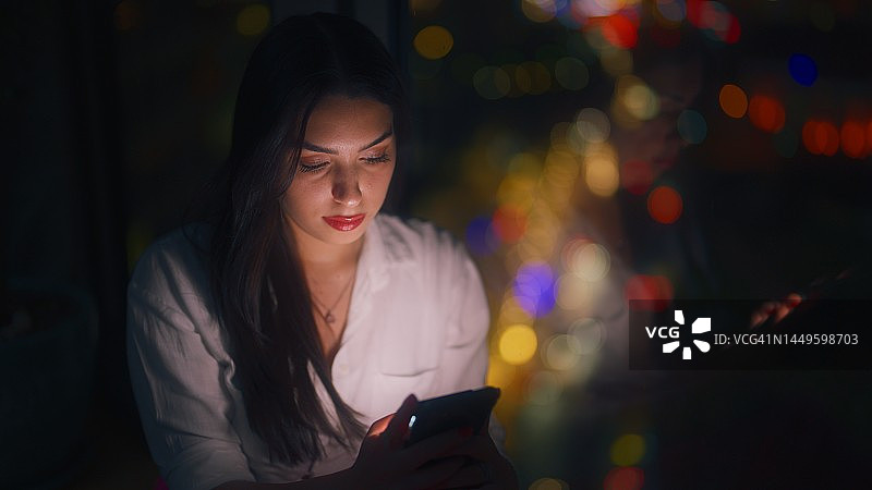 年轻女人晚上在家使用智能手机图片素材