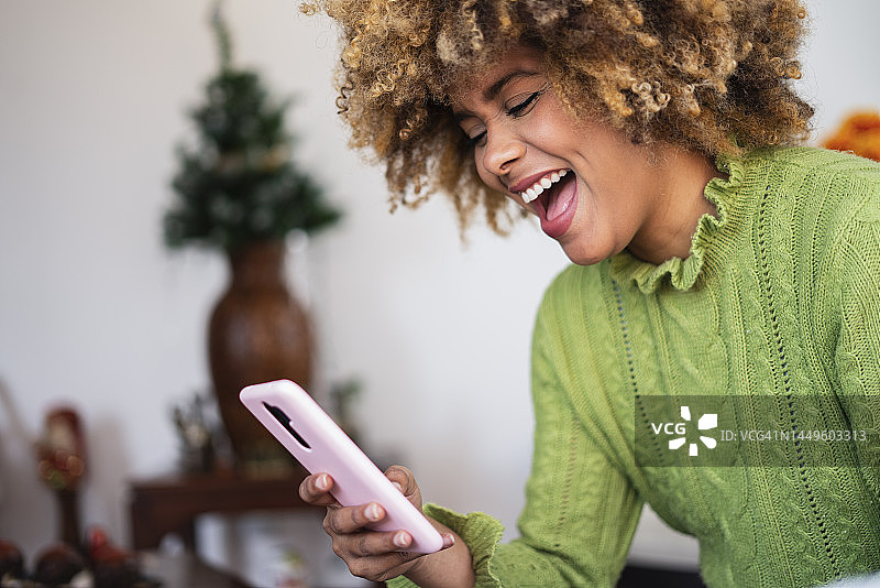 在客厅里用手机在线购物的非裔拉丁裔女性图片素材