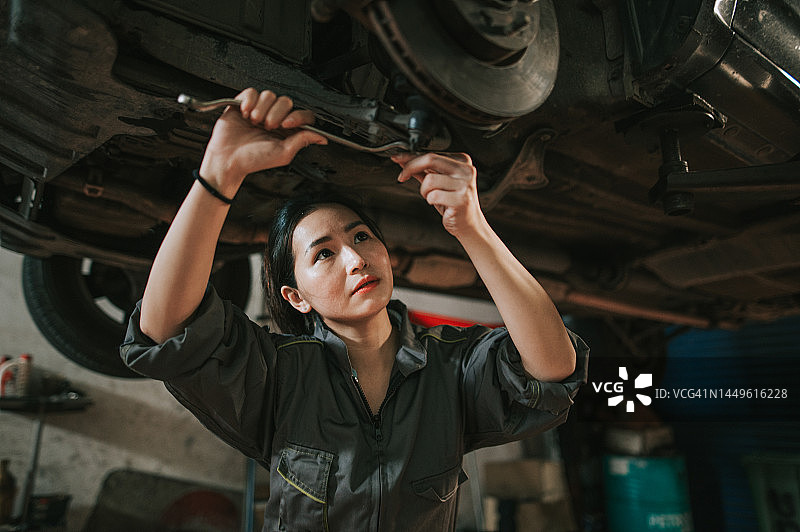 中国女技工在汽车修理店检查汽车底盘图片素材