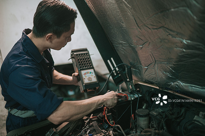 中国汽修工在汽车修理厂检查电池电量图片素材