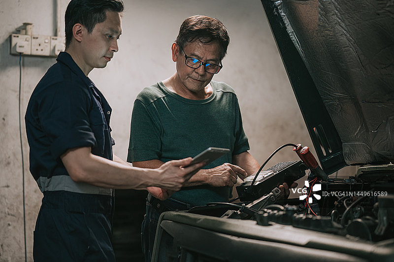 中国汽修工在汽车修理厂检查电池电量图片素材