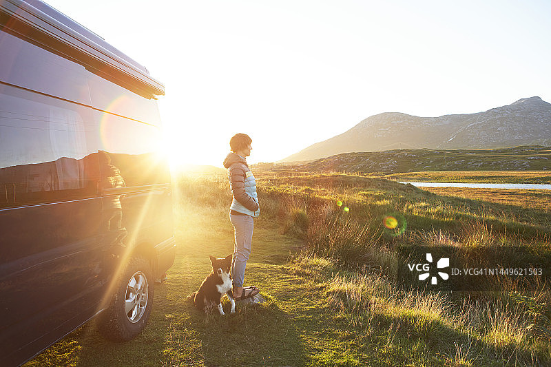 孤独的女人和她的狗在露营车旁眺望风景图片素材