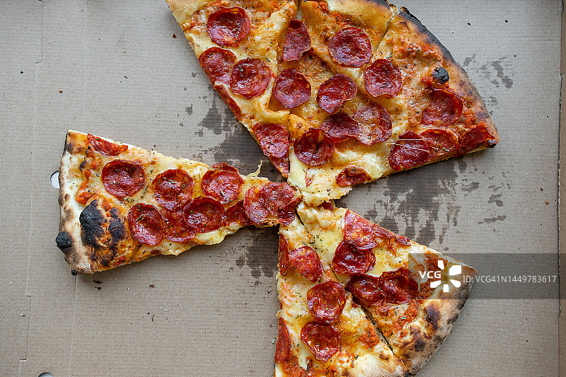 比萨店餐桌上的美味意大利比萨，配有比萨盒和外卖盒，切片比萨配有番茄、意大利辣香肠和奶酪，不健康的生活方式、暴饮暴食、垃圾食品、快餐概念，送货上门或工作场所图片素材