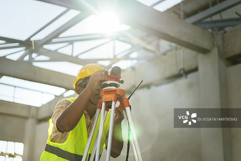 亚洲成年土木工程师在建筑工地上使用经纬仪进行测量图片素材