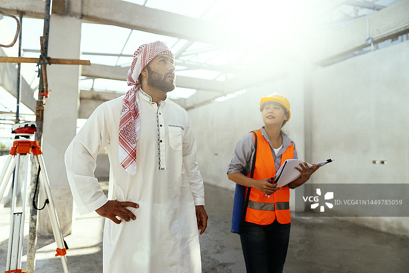 阿拉伯投资者在建筑工地上与成年女工程师一同视察，情绪积极图片素材