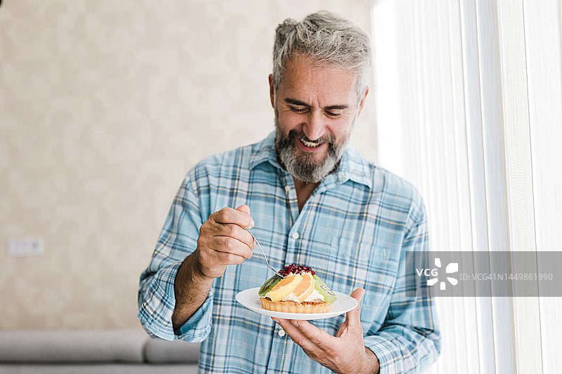 微笑的老年男人正在吃蛋糕的肖像图片素材