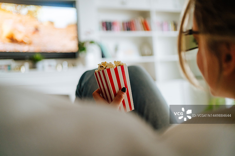 在家看电视的女人吃着爆米花图片素材