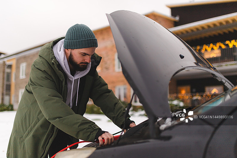 穿着冬装，在冬天启动汽车的络腮胡男子图片素材
