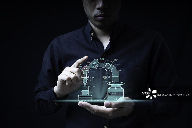 工程师指向虚拟屏幕，展示机械臂的安装和尖端技术生产线的设计图片素材