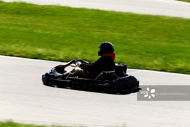 卡丁车赛道：头戴头盔的赛车手在赛道上驾驶卡丁车图片素材