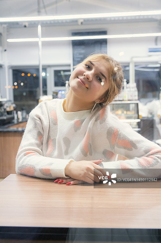 坐在舒适的咖啡馆里看着窗外的微笑少女图片素材