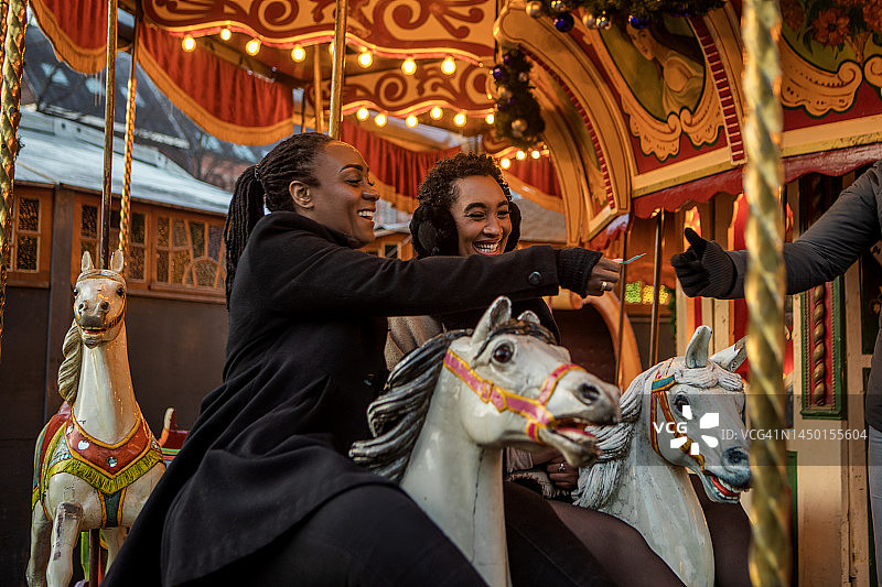 两位美丽的黑人女性在圣诞集市游乐场的一个景点上图片素材