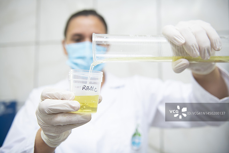 研究人员将液体从试管倒入样品容器中图片素材