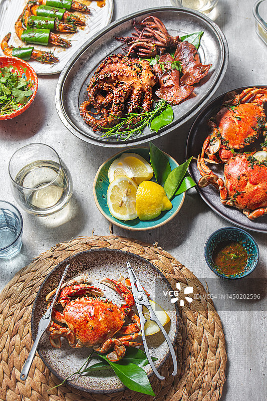 海鲜餐桌摆设：烤章鱼、鱿鱼、熟螃蟹、虾和白葡萄酒（俯视）图片素材