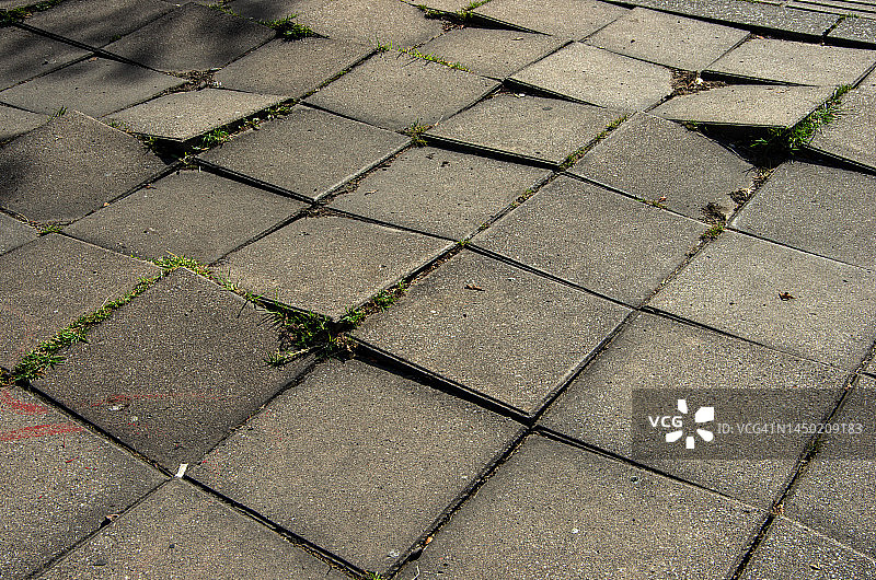 城市人行道上危险的灰色不平混凝土铺路砖图片素材