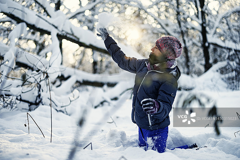 三个孩子在阳光明媚的冬日里打雪仗图片素材