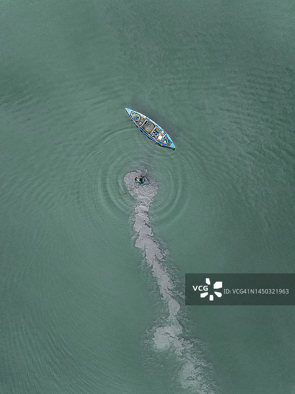 一名渔民涉水走向传统渔船，无人机拍摄，越南图片素材