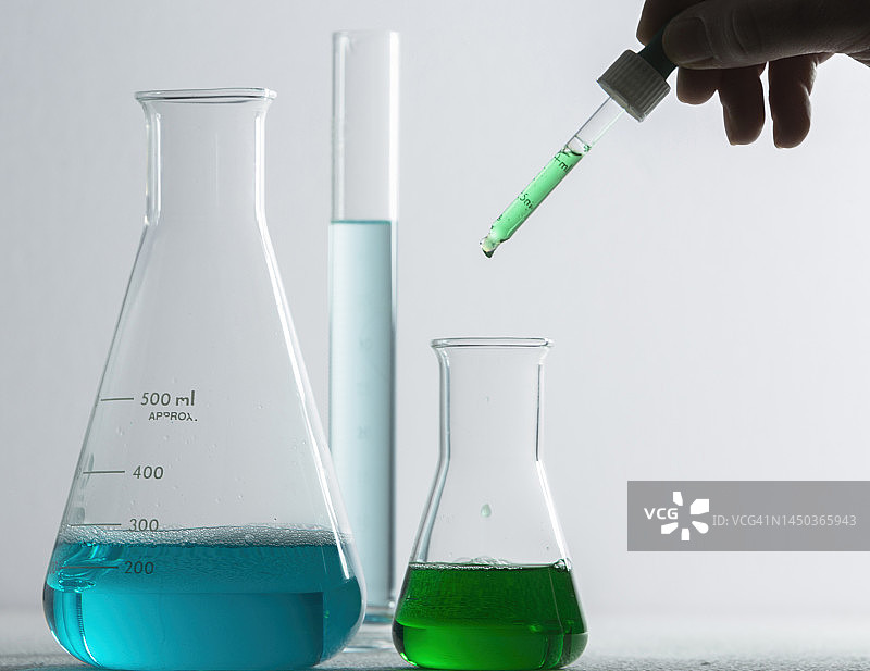 实验人员用移液管将化学品滴入烧瓶图片素材