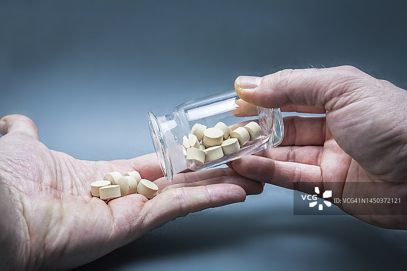 手从瓶子里倒出药丸图片素材