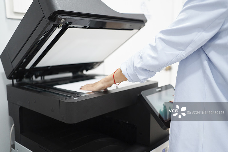 在办公室使用电脑打印机的白人女性的手部特写。该女士正在为即将举行的公司董事会商务会议制作复印件图片素材