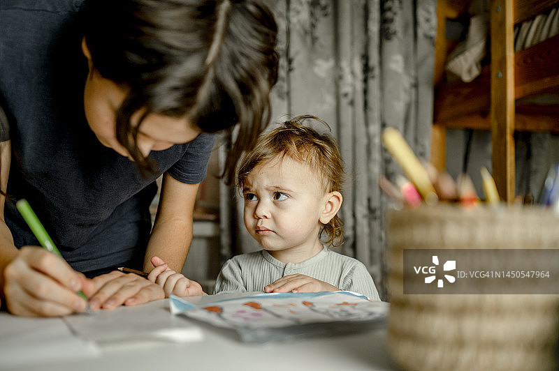 在家写字的哥哥旁悲伤的男婴图片素材