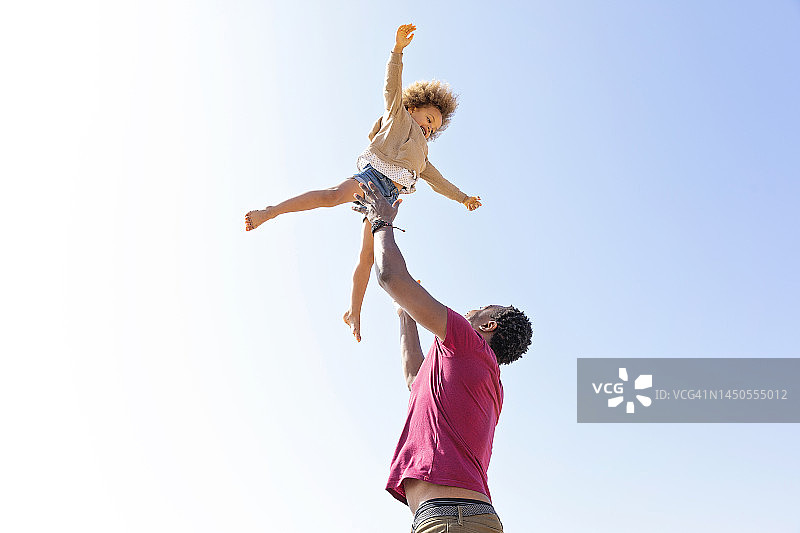 活泼父亲晴空下抱女儿图片素材