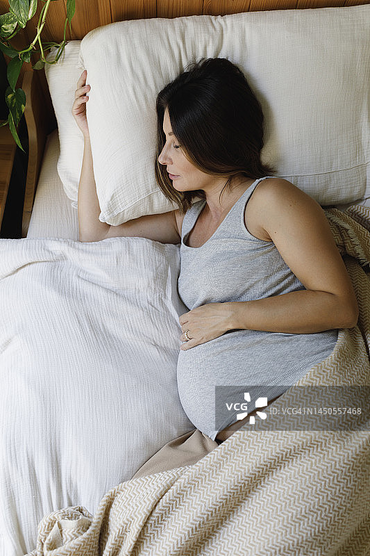 怀孕的中年妇女在家里的床上睡觉图片素材