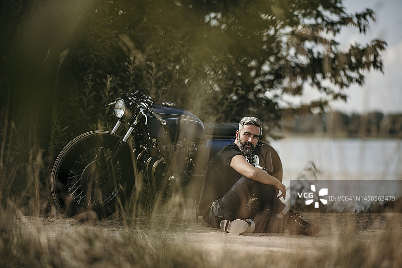 坐在摩托车前的沉思的成熟男人图片素材