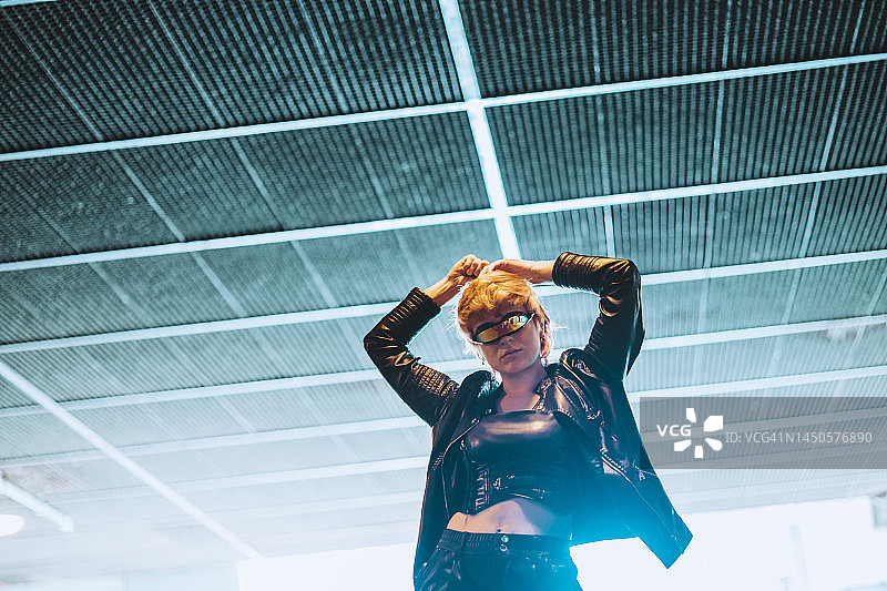 在天花板下举起双臂的自信年轻女人图片素材