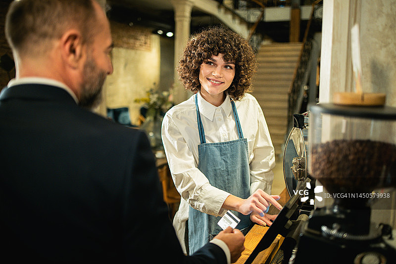 女服务员在咖啡馆向顾客收费图片素材