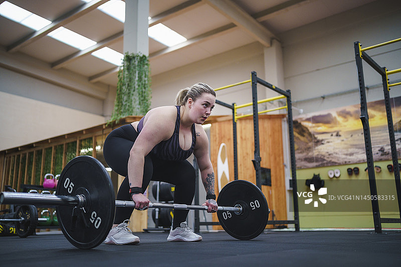 自信的超重女人在健身房用杠铃锻炼图片素材