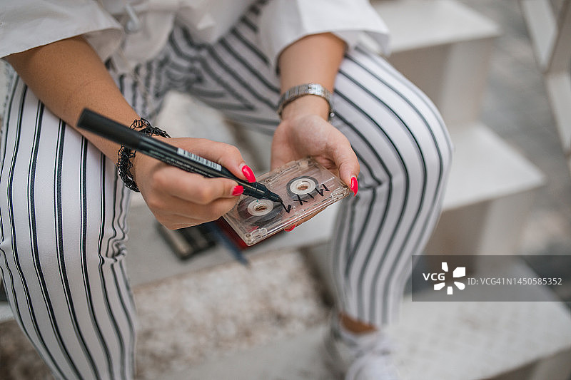 女人用记号笔在音乐磁带上写字图片素材