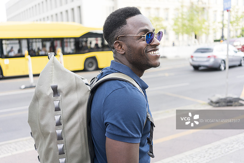 快乐的男人背着背包走在人行道上图片素材