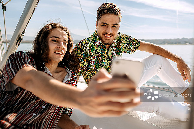 两个年轻的男性朋友一起乘坐游艇时自拍图片素材