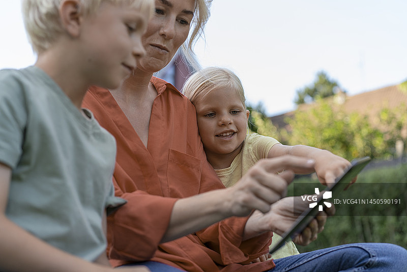 与孩子们坐在一起使用平板电脑的女人图片素材