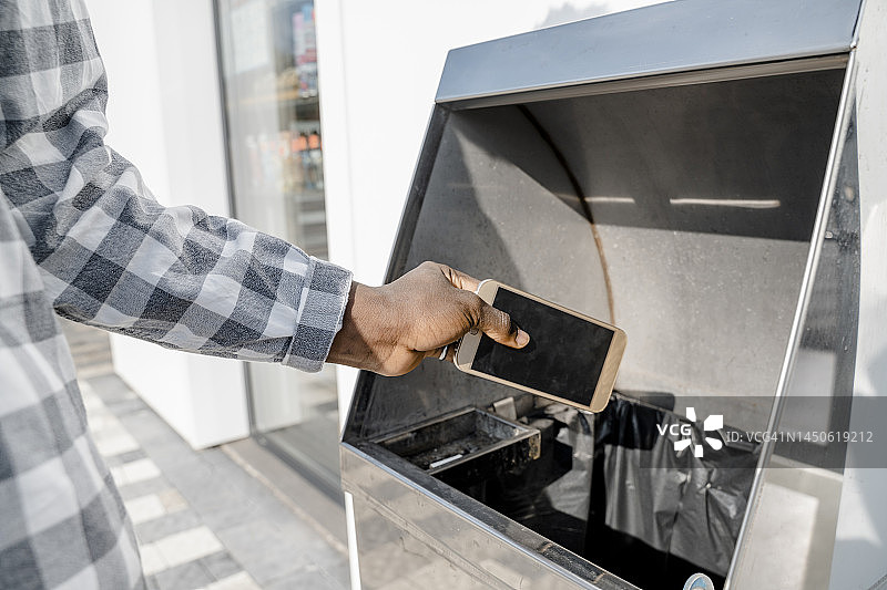 男子将智能手机扔进垃圾桶图片素材