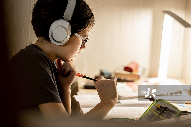 戴着无线耳机在家做作业的男孩图片素材