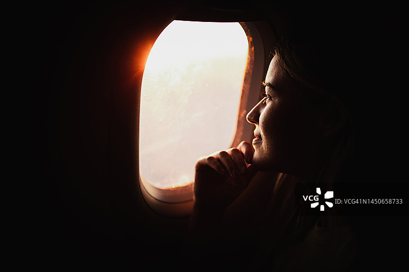 沉思的女人透过飞机窗户看日落图片素材