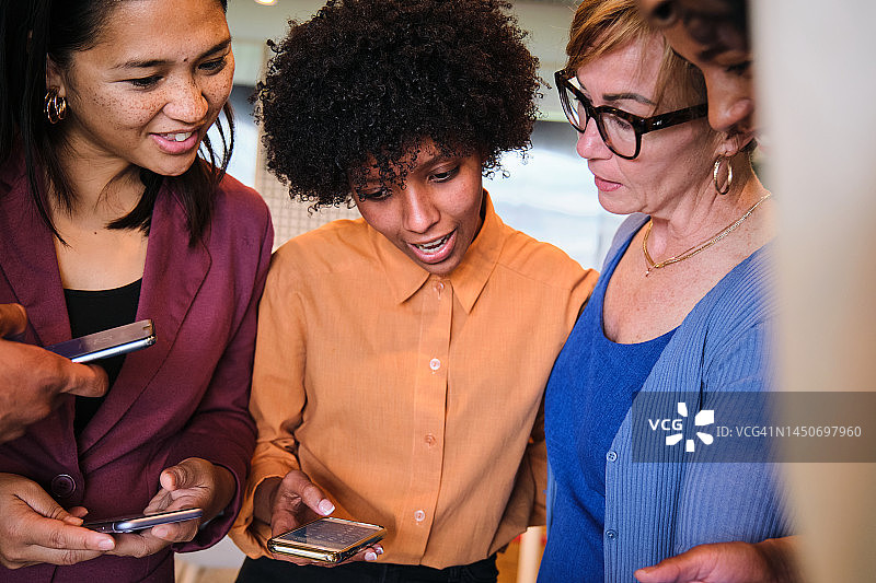 笑容满面的女商人在办公室休息期间查看手机图片素材