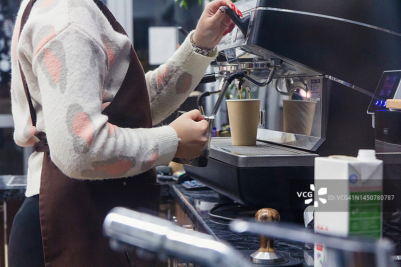 咖啡馆员工在商用厨房用咖啡机制作卡布奇诺图片素材