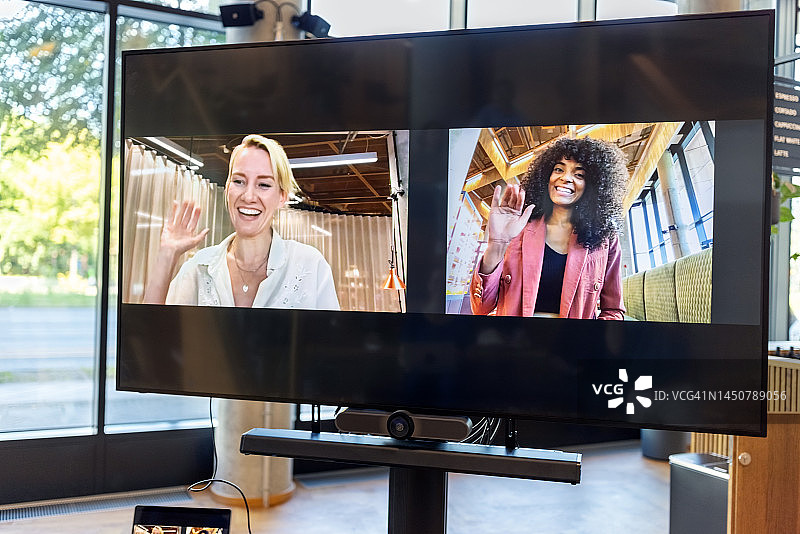 在视频会议中挥手的女商人（电视屏幕）图片素材
