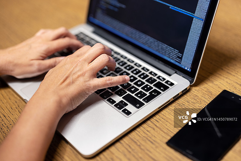 男子在桌子上的笔记本电脑键盘上打字的特写图片素材