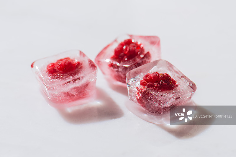 白色大理石表面冰块中的冷冻覆盆子图片素材