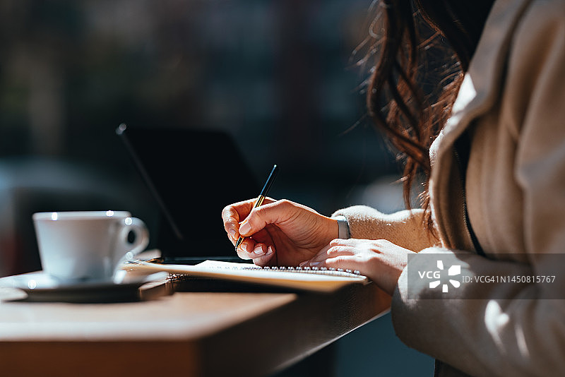 在咖啡馆里写笔记本的匿名女人图片素材