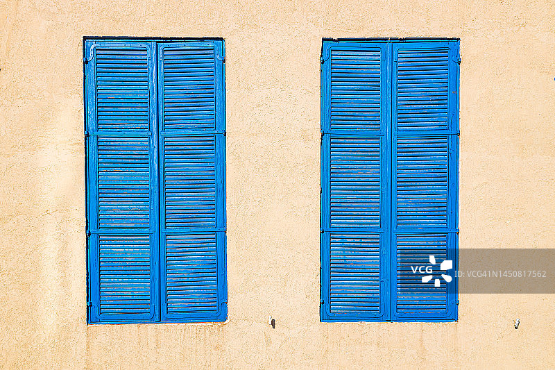 黄色墙壁上的两扇蓝色百叶窗图片素材